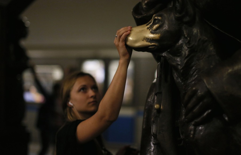 People touch the statue of a dog at the Ploshchad Revolyutsii metro station